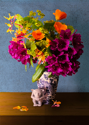 A small friendly gargoyle sits next to an oriental vase filled with scarlet and orange blossoms.