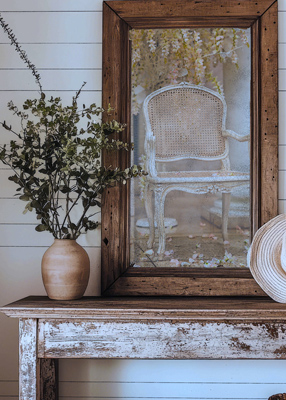 A white chair is reflected in a wooden mirror.